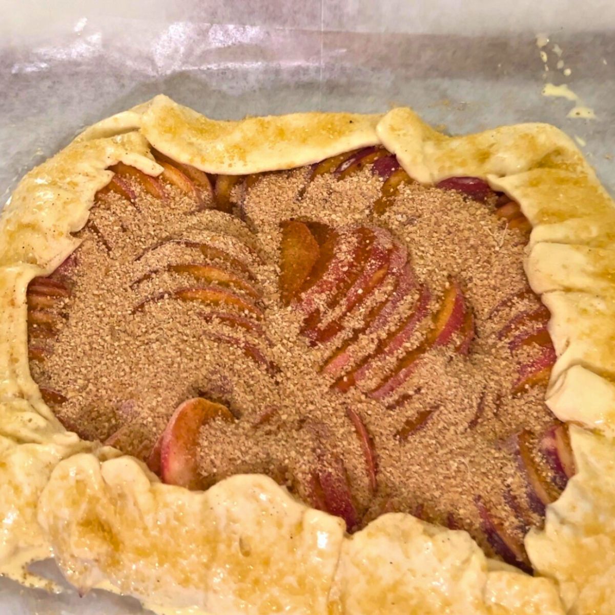 Puff pastry galette with peaches and cinnamon sugar ready for baking.