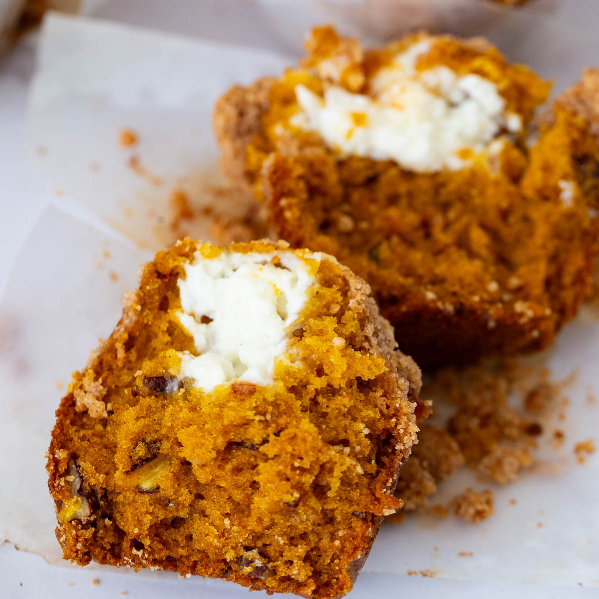 Muffin with cream cheese and crumble on the plate.