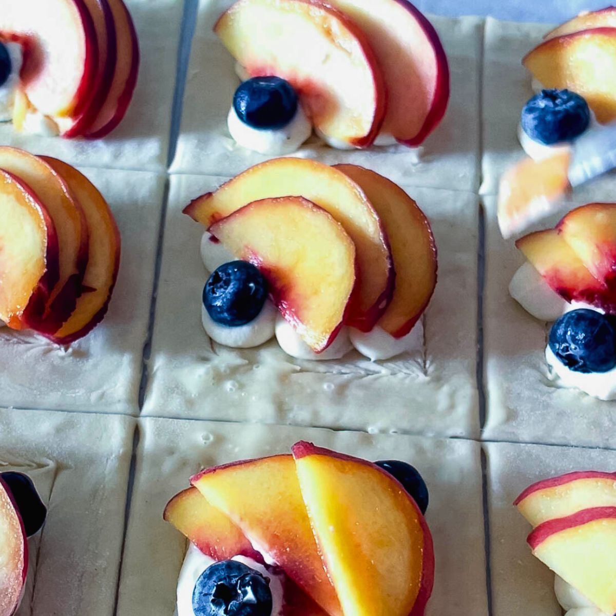 Freshly baked blueberry peach puff pastry tarts with flaky, golden edges.