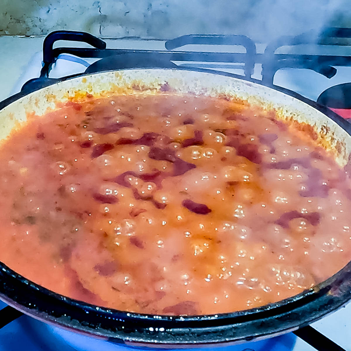 Stirring tomato paste and spices into sautéed onions in a skillet.
