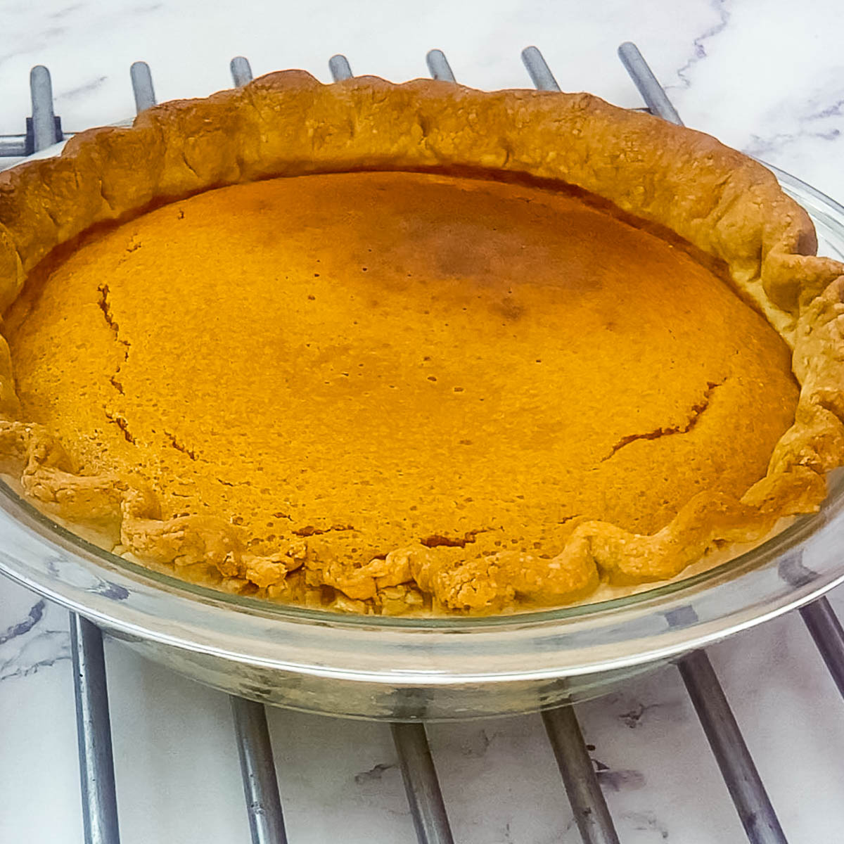 Baked pumpkin pie on wire rack.