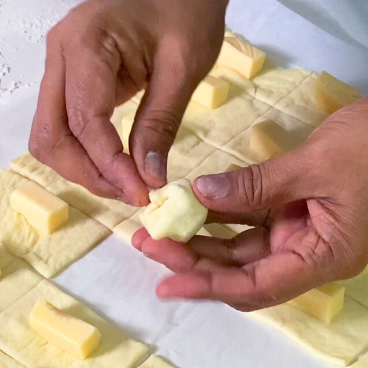 Wrap each pizza dough with cheese cube.