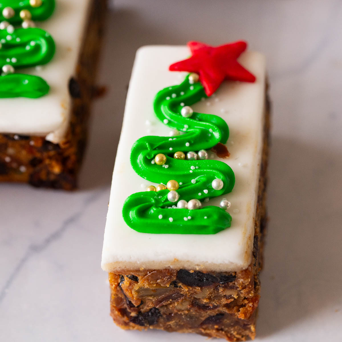A mini fruitcake on the table with a piped Christmas tree.