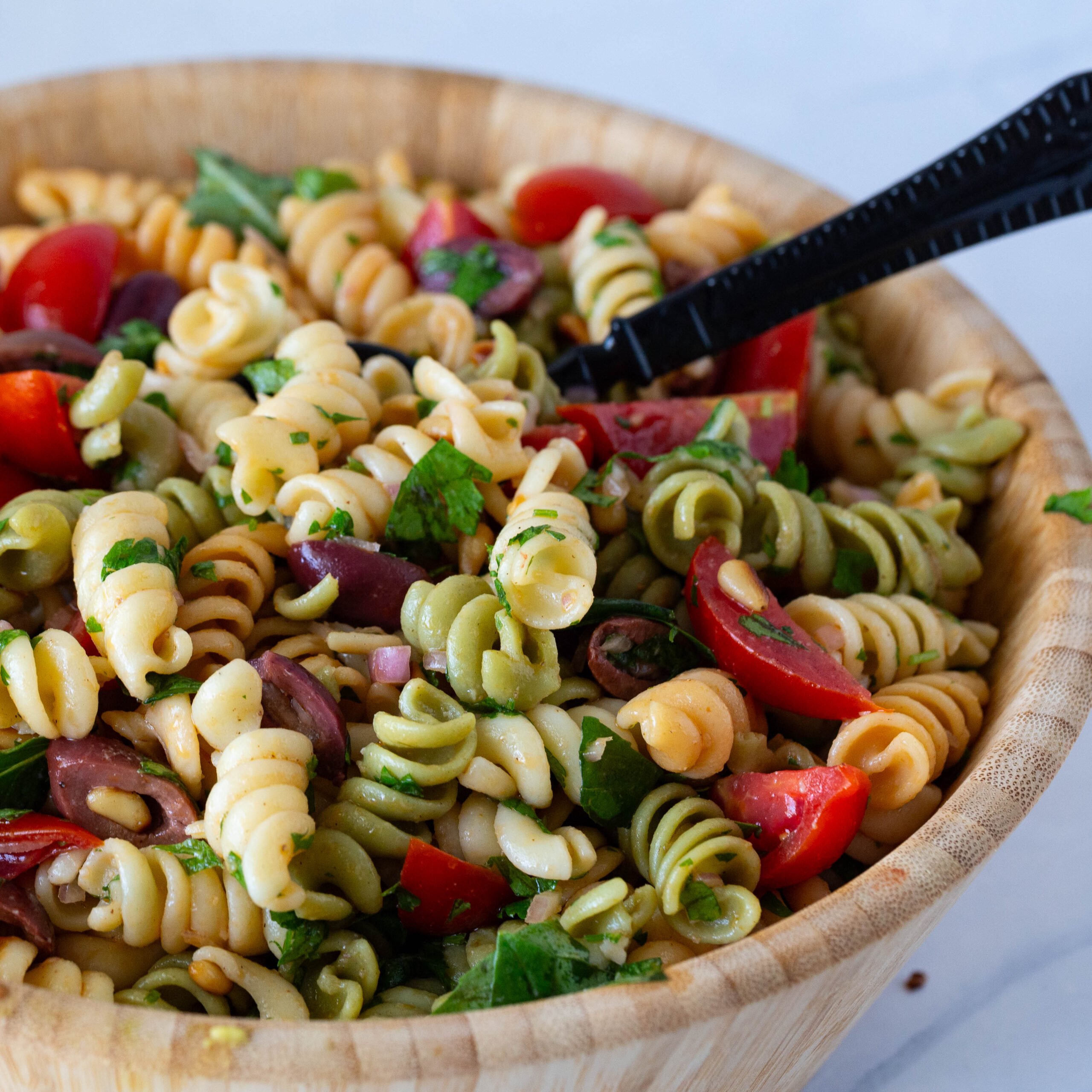 A wooden bowl with colorful pasta salad.