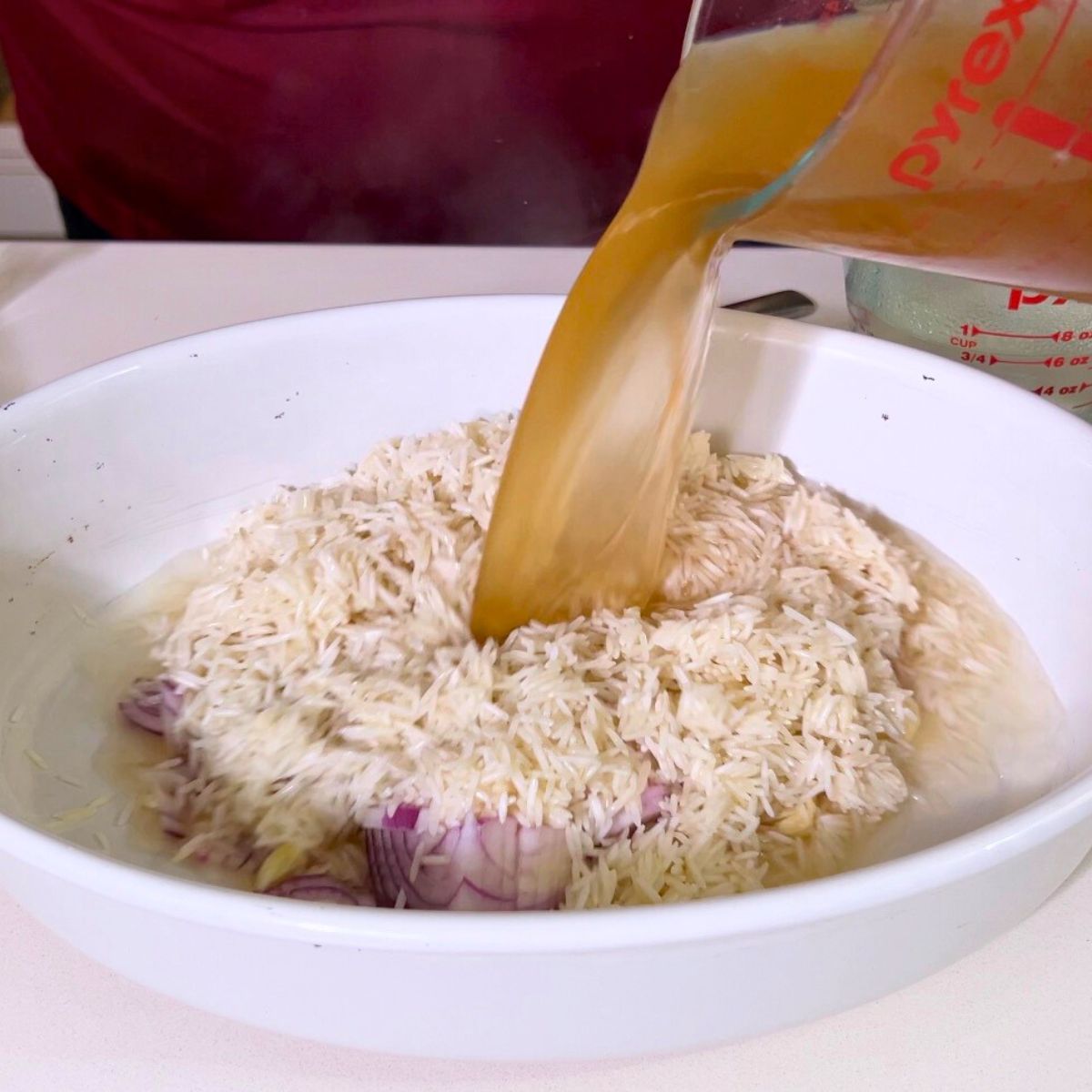 A baking dish with raw rice and chicken in pan.