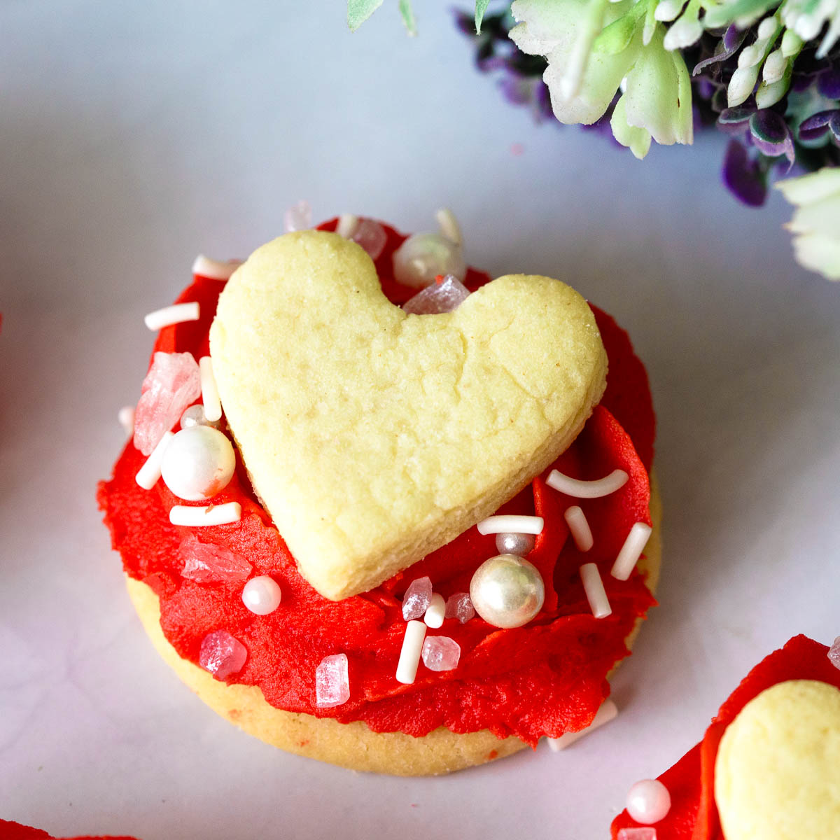 Red Buttercream Rose with Heart Cookie on top.