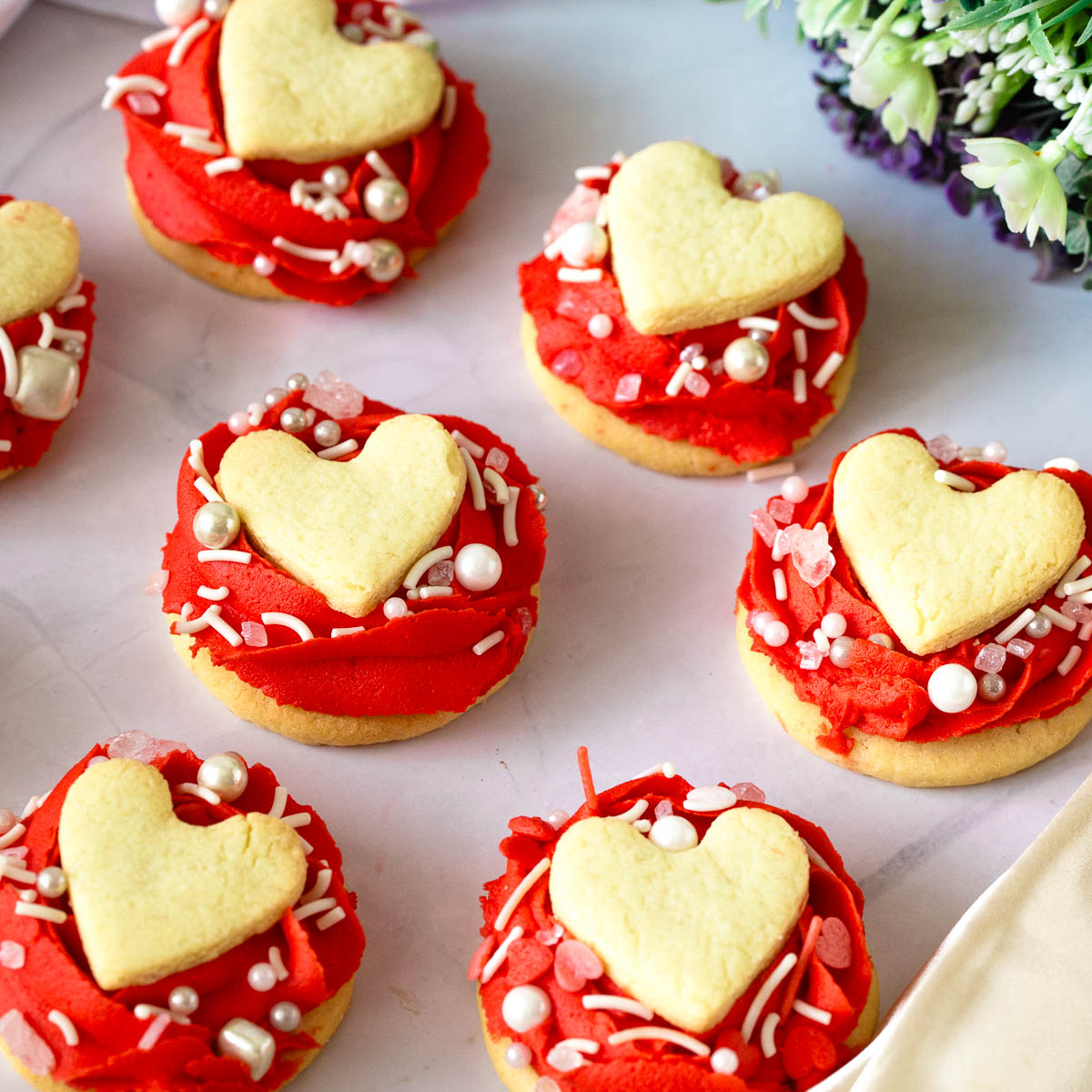 Red Buttercream roses frosted on valentine sandwich cookies.
