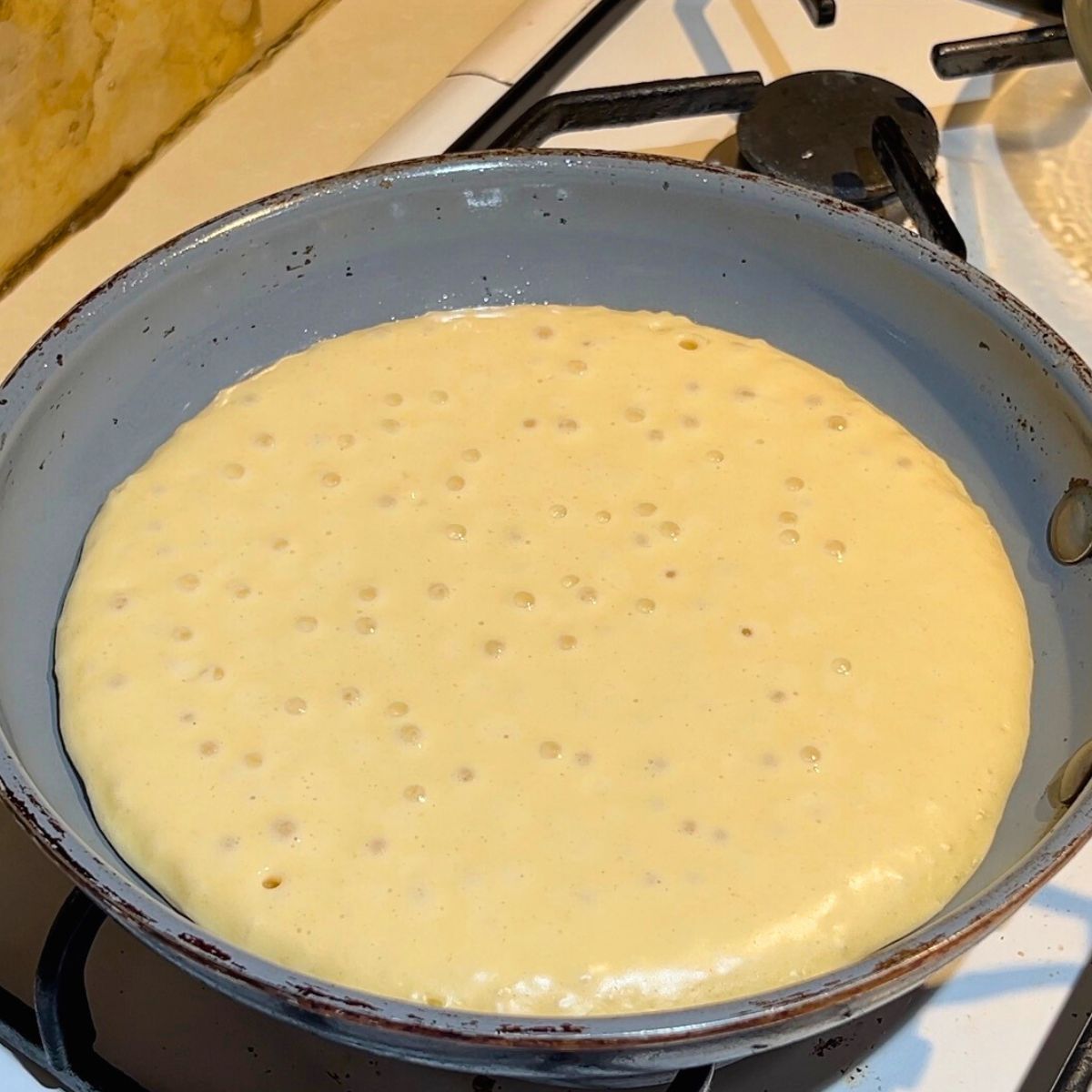 Pancake cooking on a frying pan.
