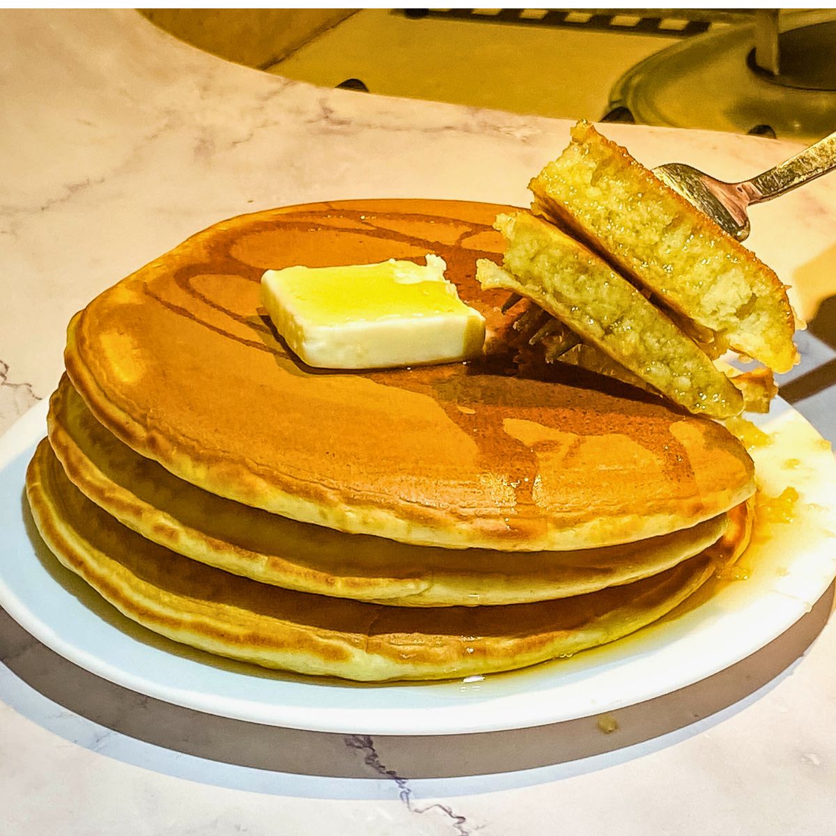 A stack of pancakes on a white plate.