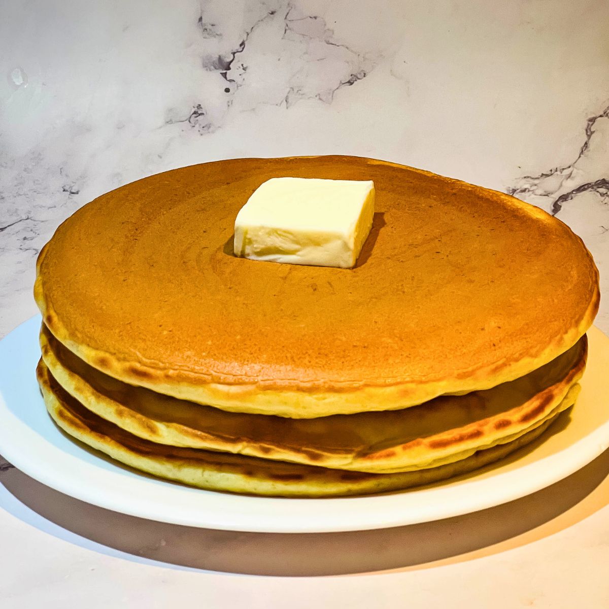 Three big fluffy pancakes on a plate.