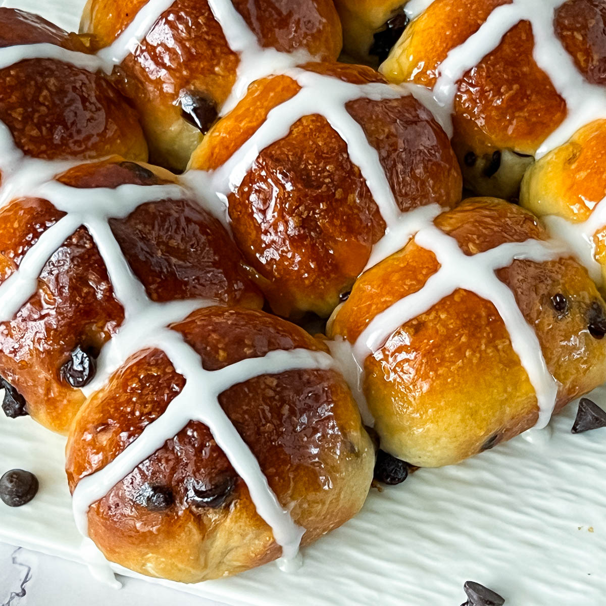 Hot cross buns with chocolate chips and icing cross on the table.
