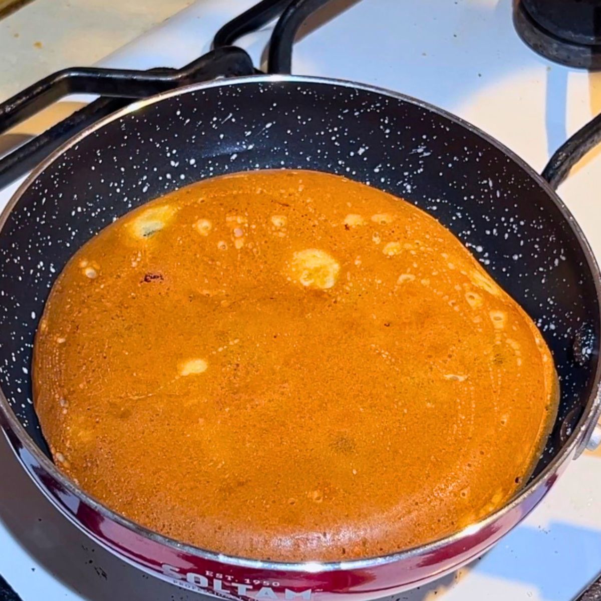 A frying pan with cooked blueberry pancake.