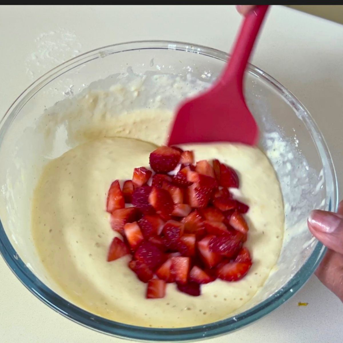 Pancake batter with fresh strawberries in a glass bowl.