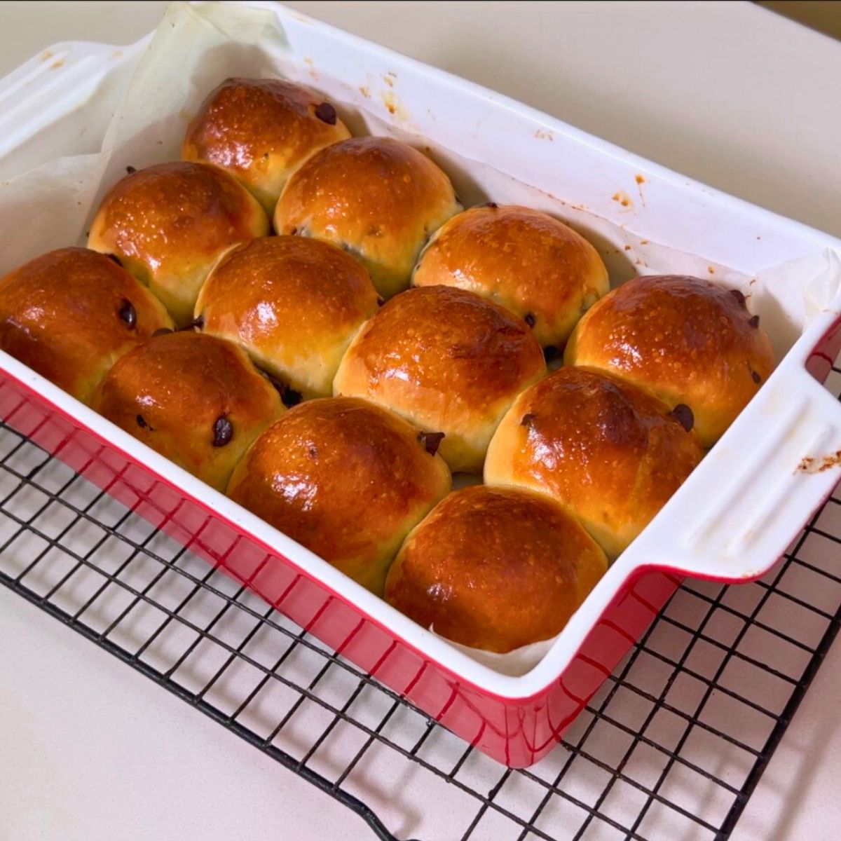 Fresh baked hot cross buns in a baking pan.