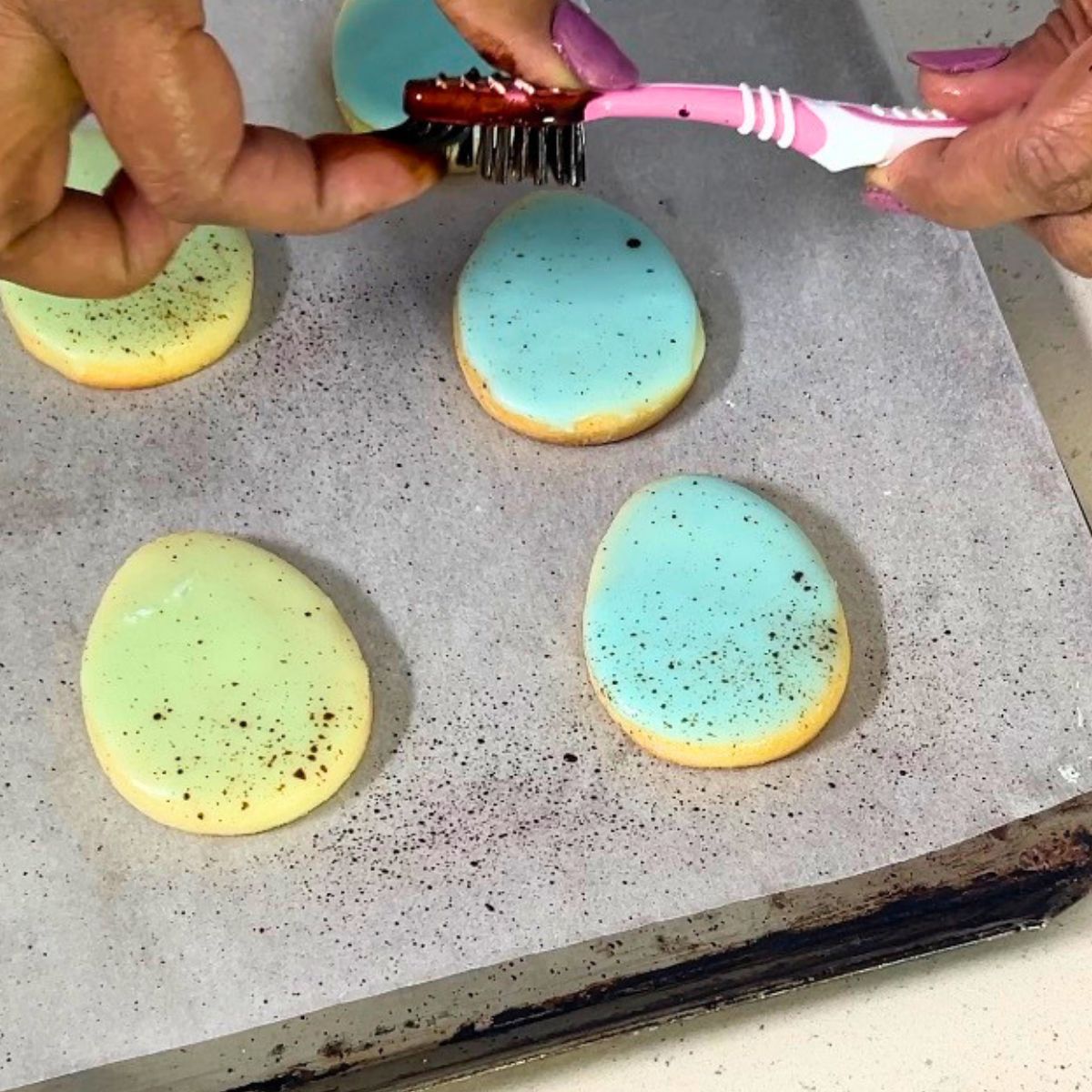 Speckling the easter glazed sugar cookies.