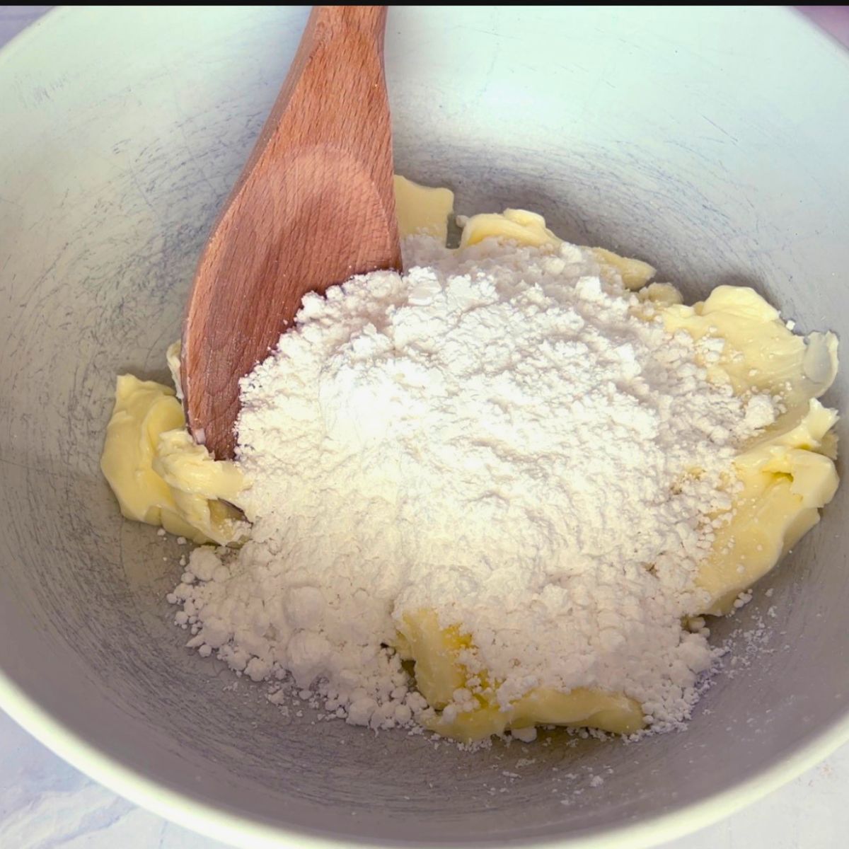 Creaming butter and powdered sugar in a bowl.