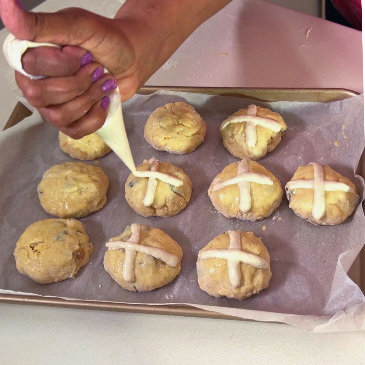 Piping flour cross on the hot cross buns.