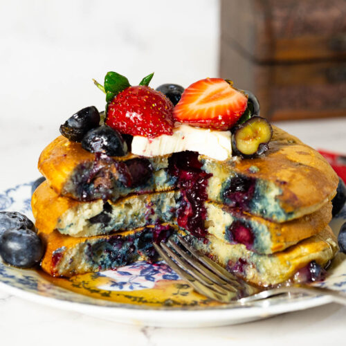 A plate with a stack of fresh blueberry pancakes.