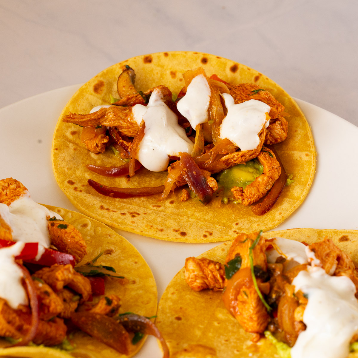 A plate with chicken tacos, veggies and yogurt.