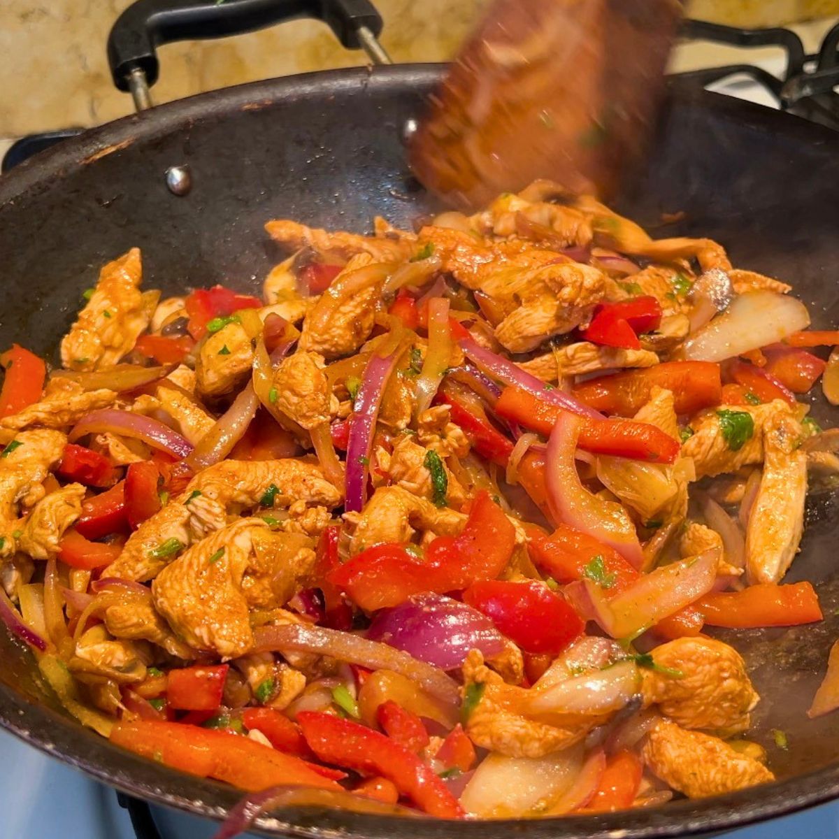 A skillet with fresh made chicken and veggies in taco seasoning.