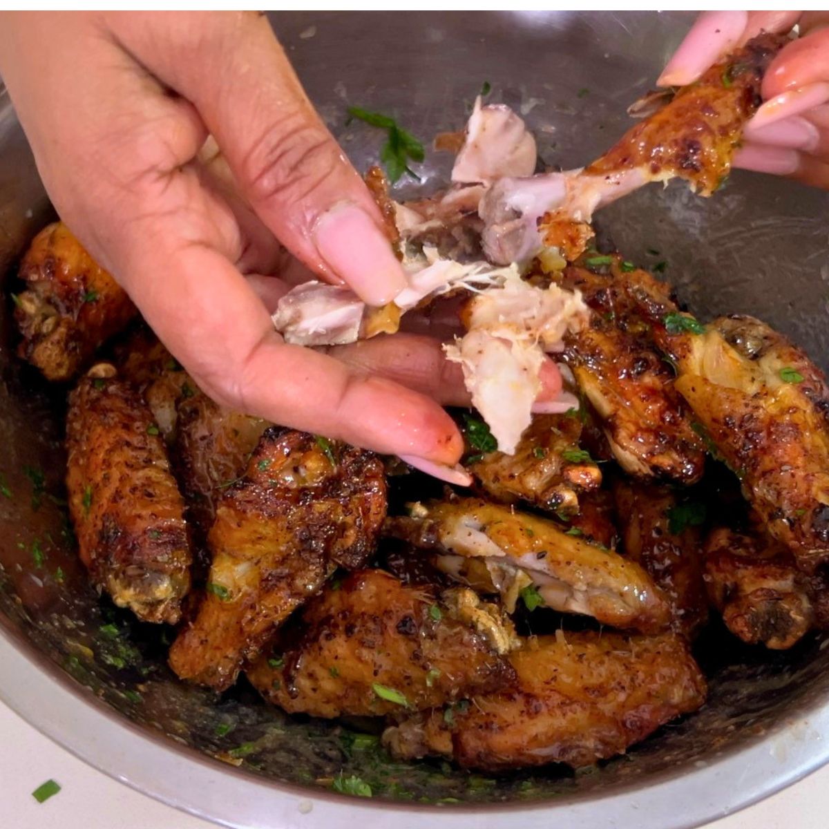 Shredding chicken wings drizzled with lemon butter.
