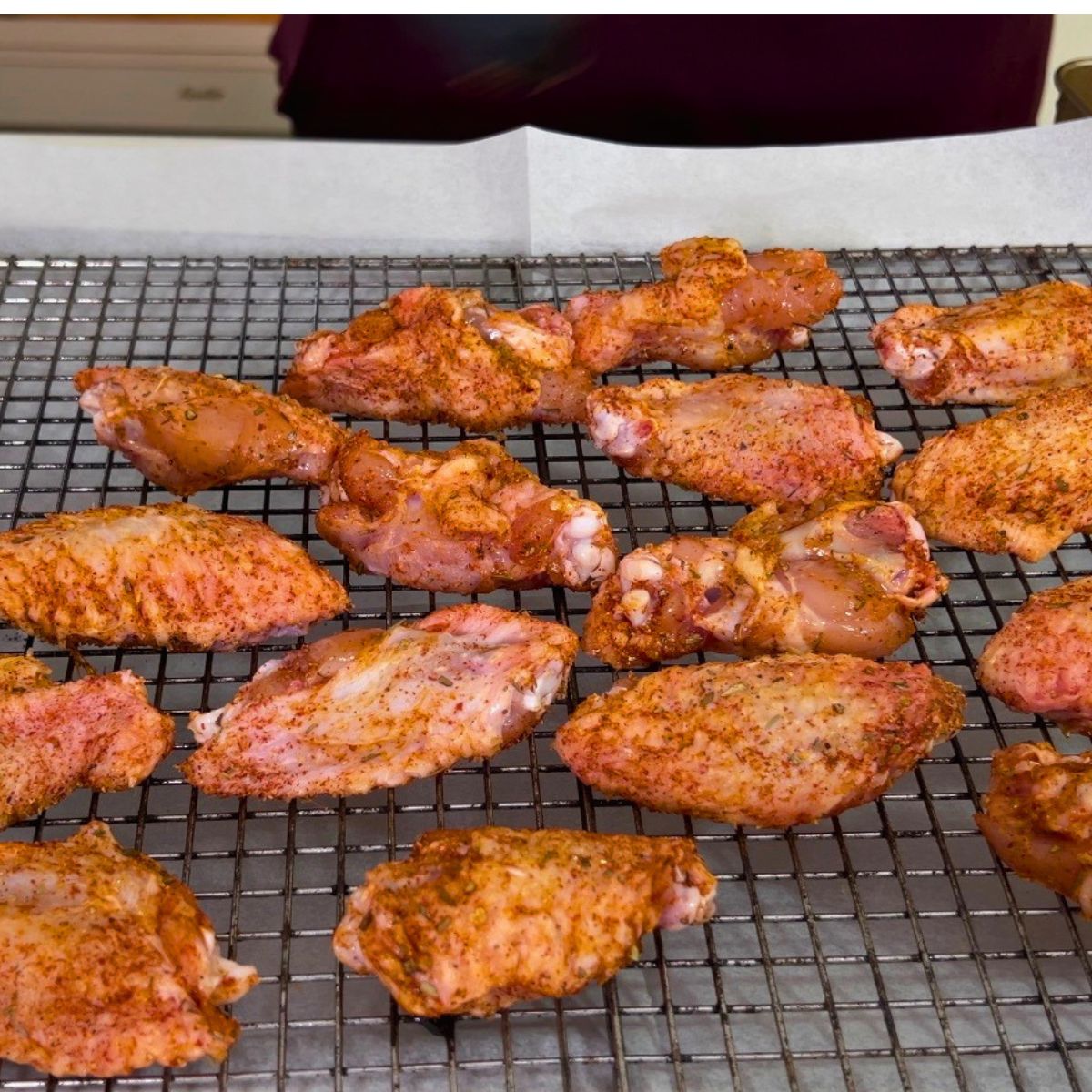 Seasoned chicken wings on a wire rack for baking.