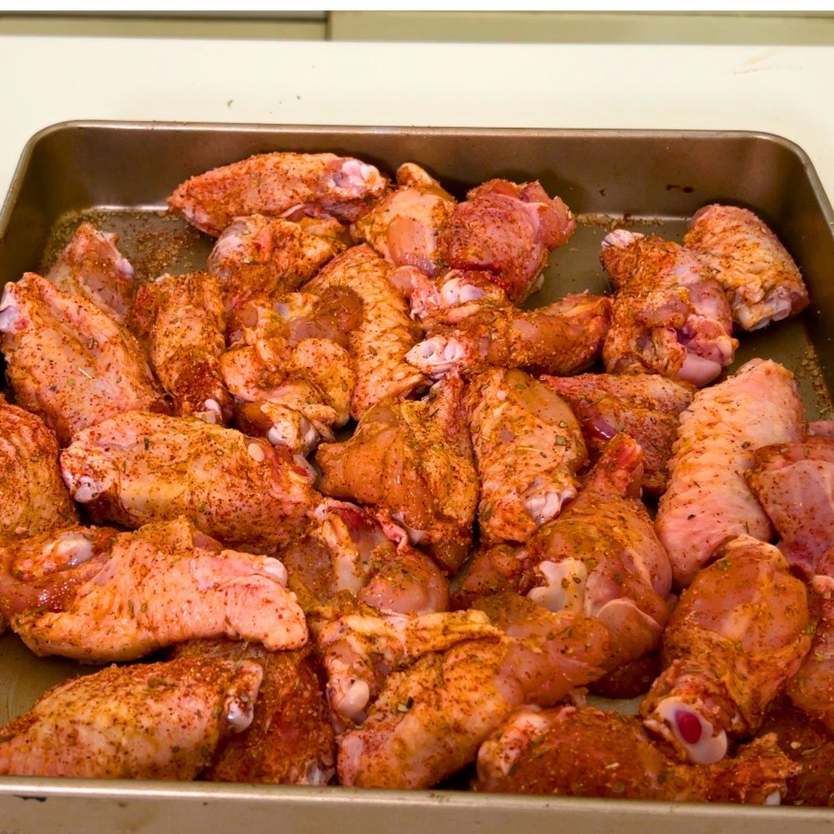 A baking tray with creole seasoned chicken wings.