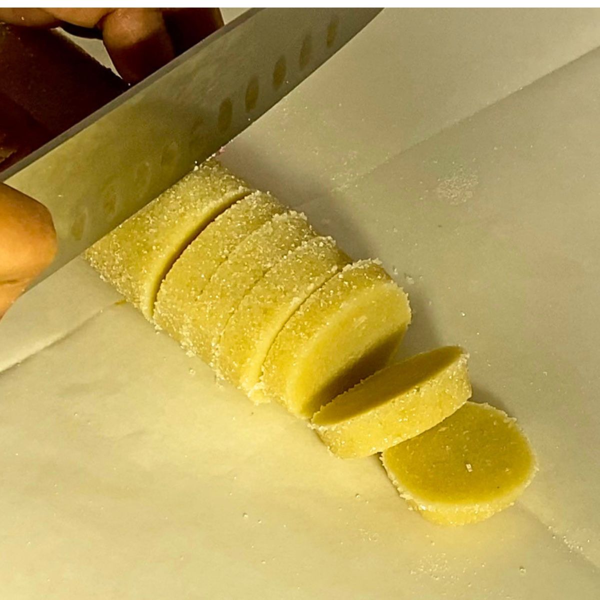 Slicing a log of cookie dough for baking.