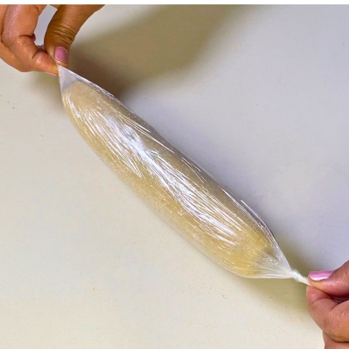 Wrapping a cookie dough long in plastic wrap.