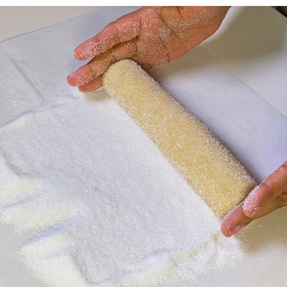 Rolling the cookie dough log in sugar.