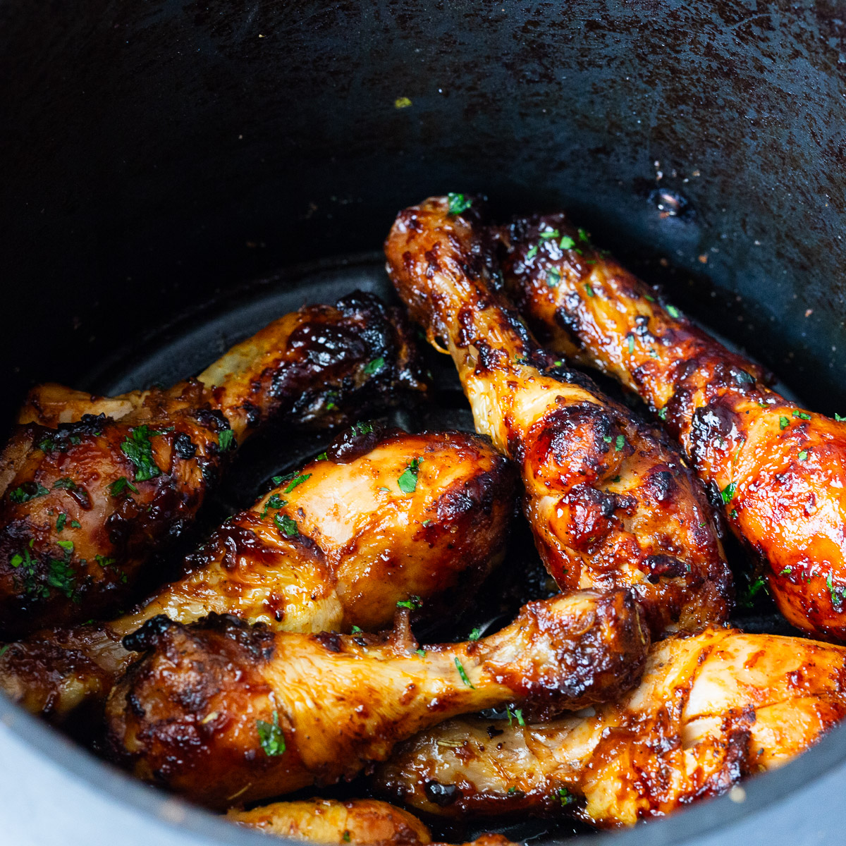 An air fryer basket with BBQ chicken legs.