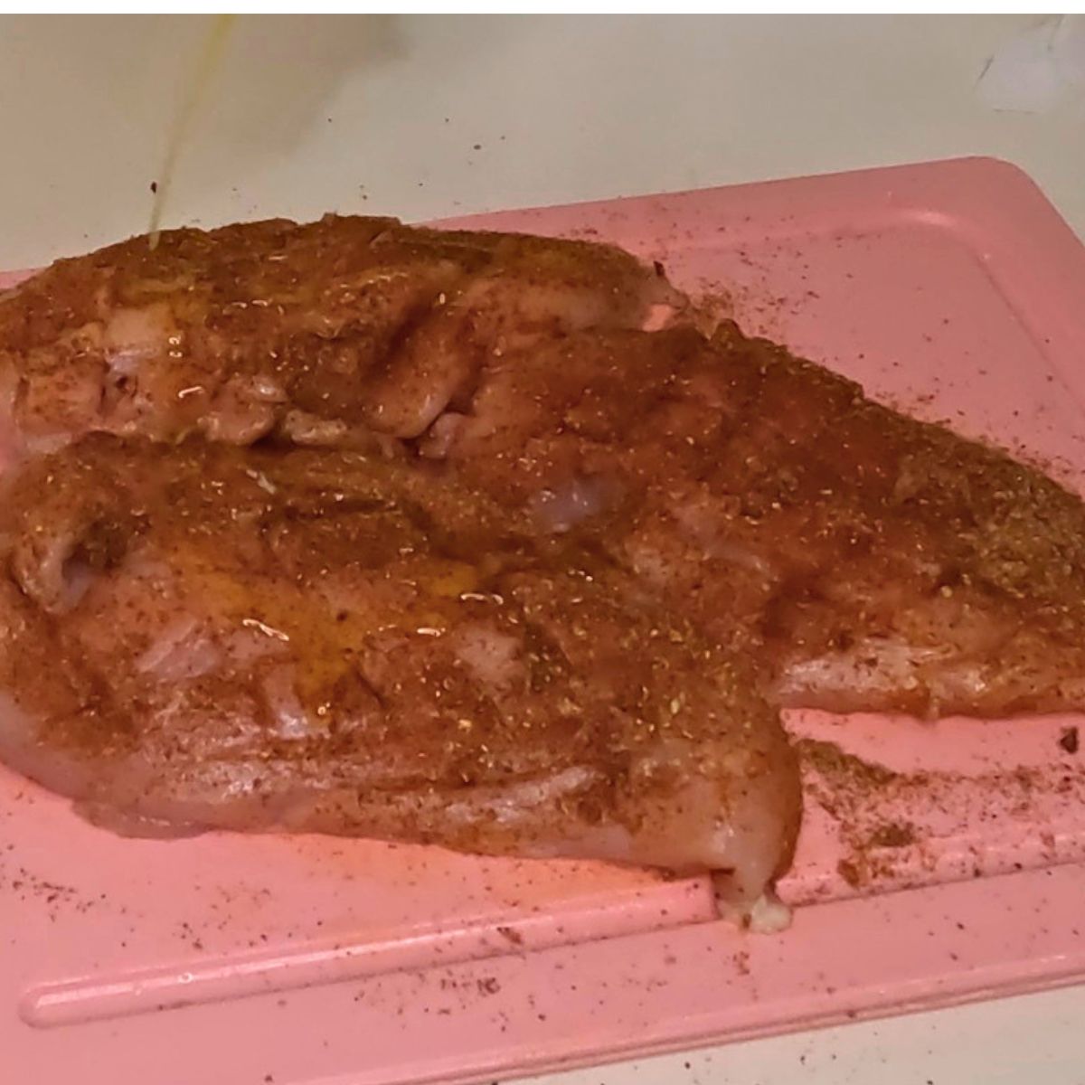 Chicken breast on a board with spices.