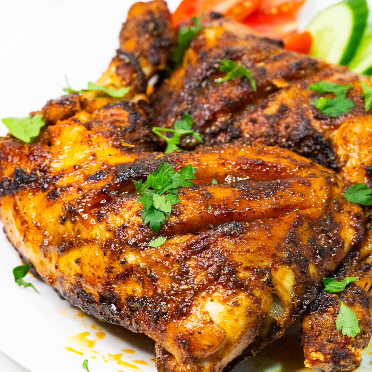 Chicken quarters baked in an air fryer on a white plate.