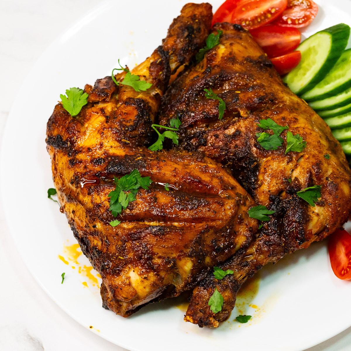 A white plate with baked chicken quarters.