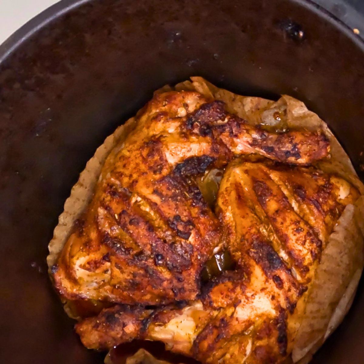 Air fryer basket with chicken quarters.