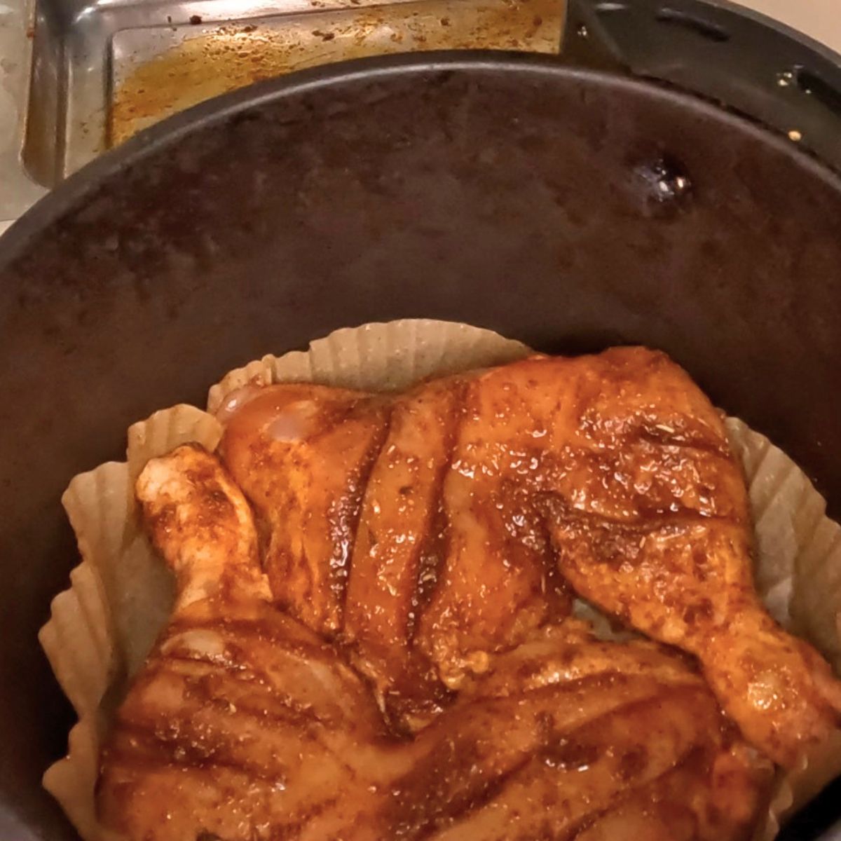 An air fryer basket with chicken quarters.