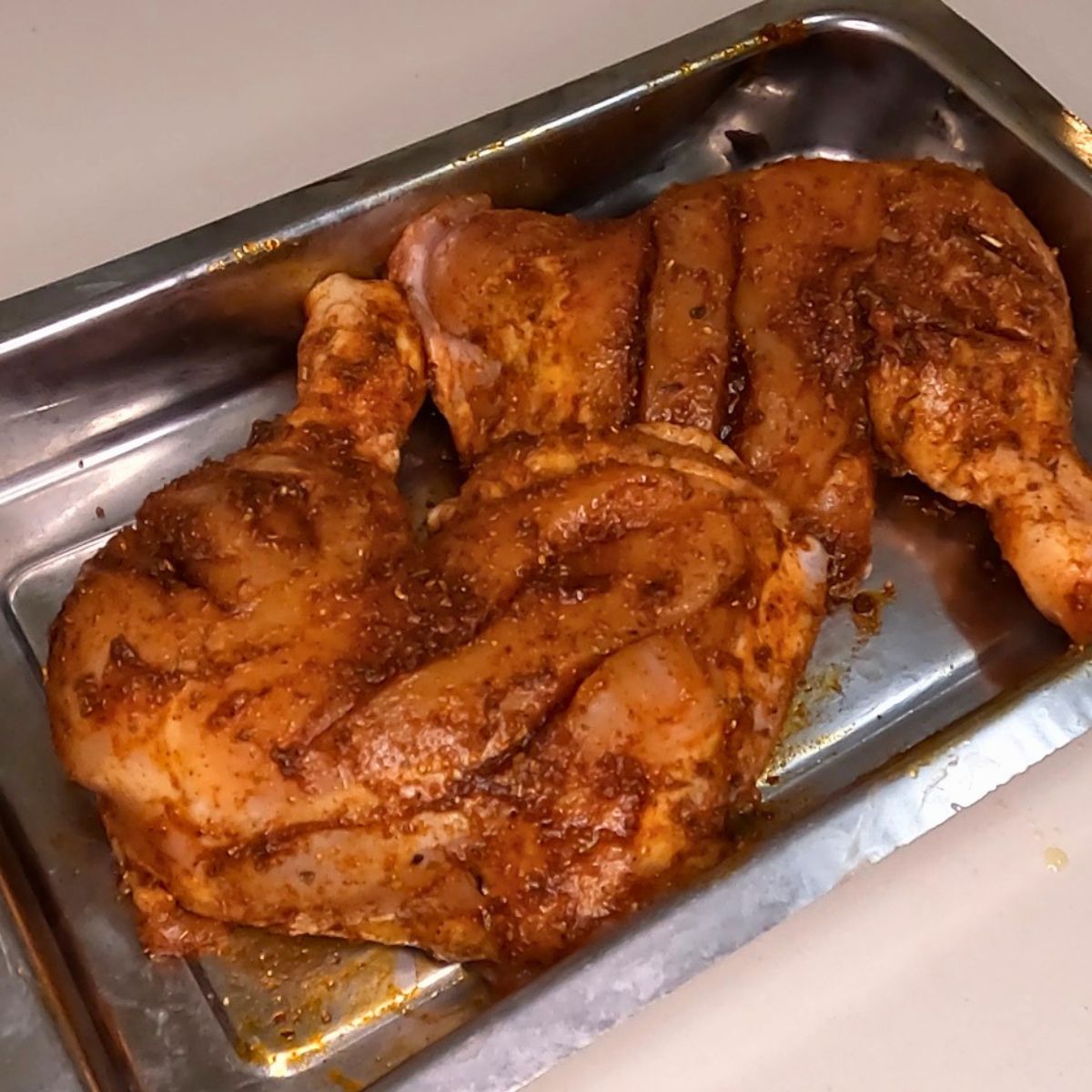 A baking dish with spiced air fryer chicken quarters.
