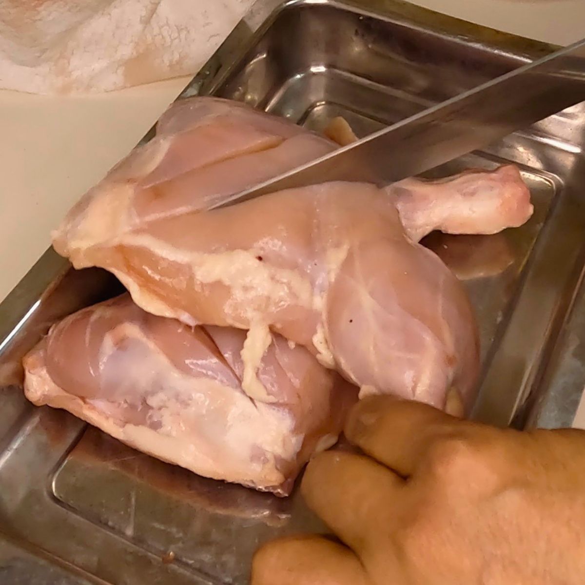 A marinating dish with chicken quarters.