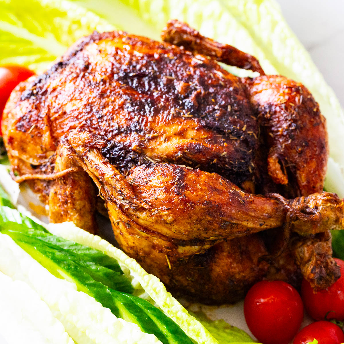A whole roast chicken on lettuce.