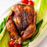 A whole roast chicken on lettuce.