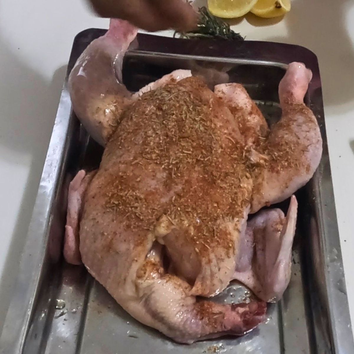 A tray with whole chicken and dry rub.