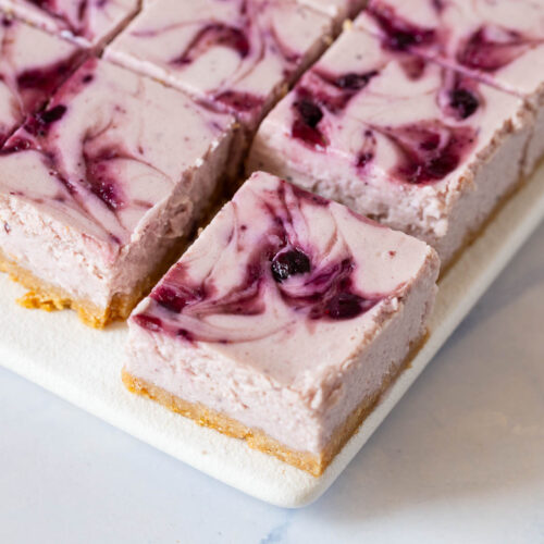 Cheesecake bars with blueberry swirl on the tray.