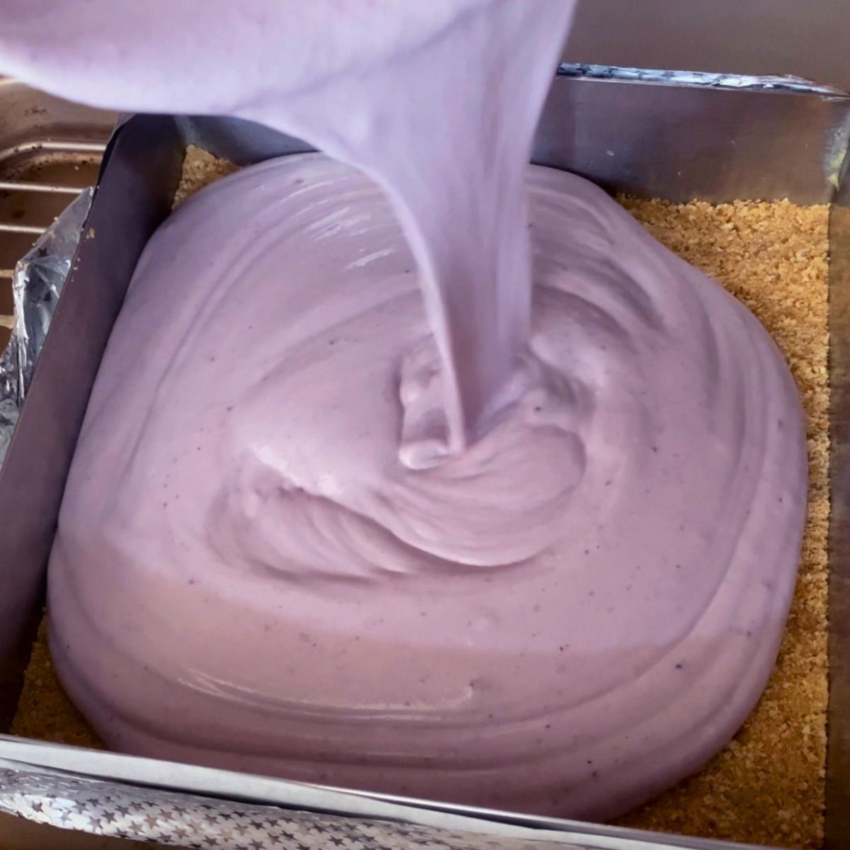 Pouring cheesecake batter into the baking pan.