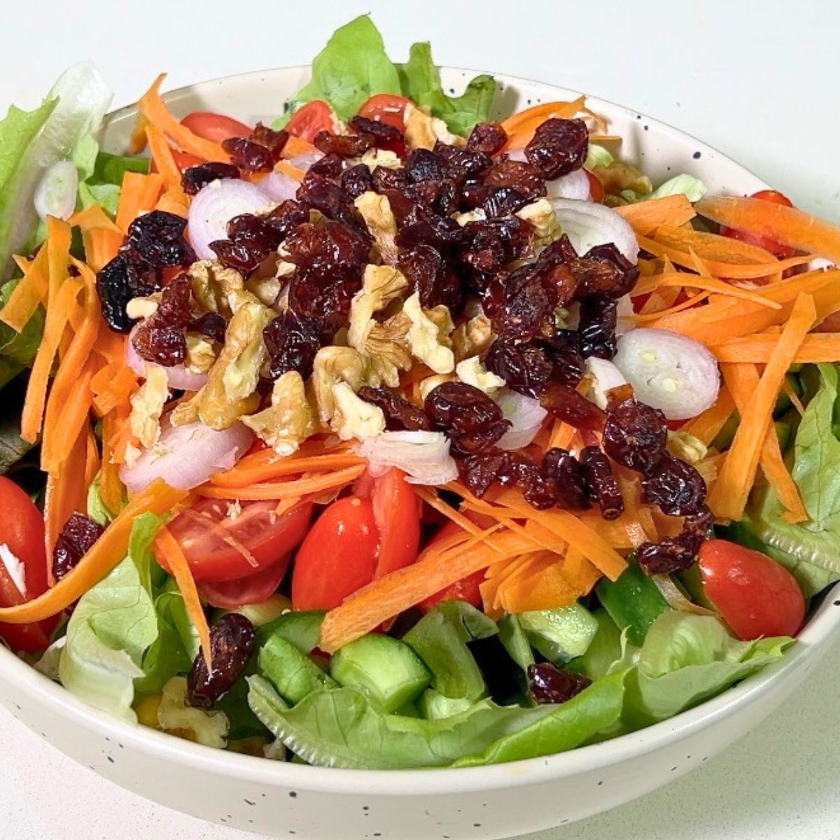 A bowl with salad veggies and honey mustard dressing.