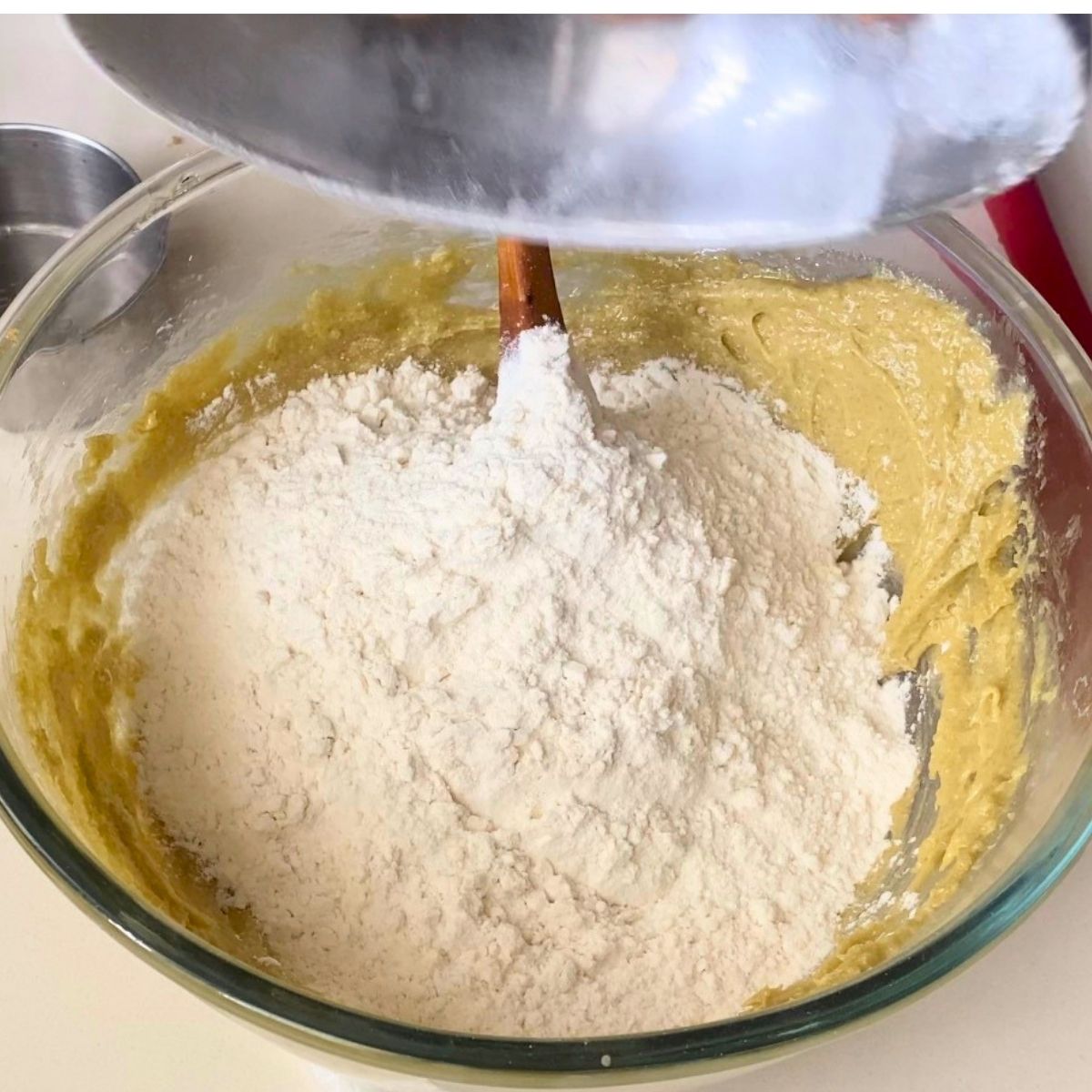 Adding flour to the cookies dough in glass bowl.