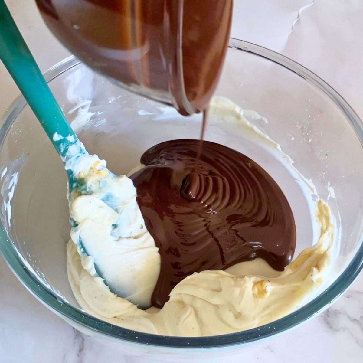Adding melted chocolate to the cream cheese.