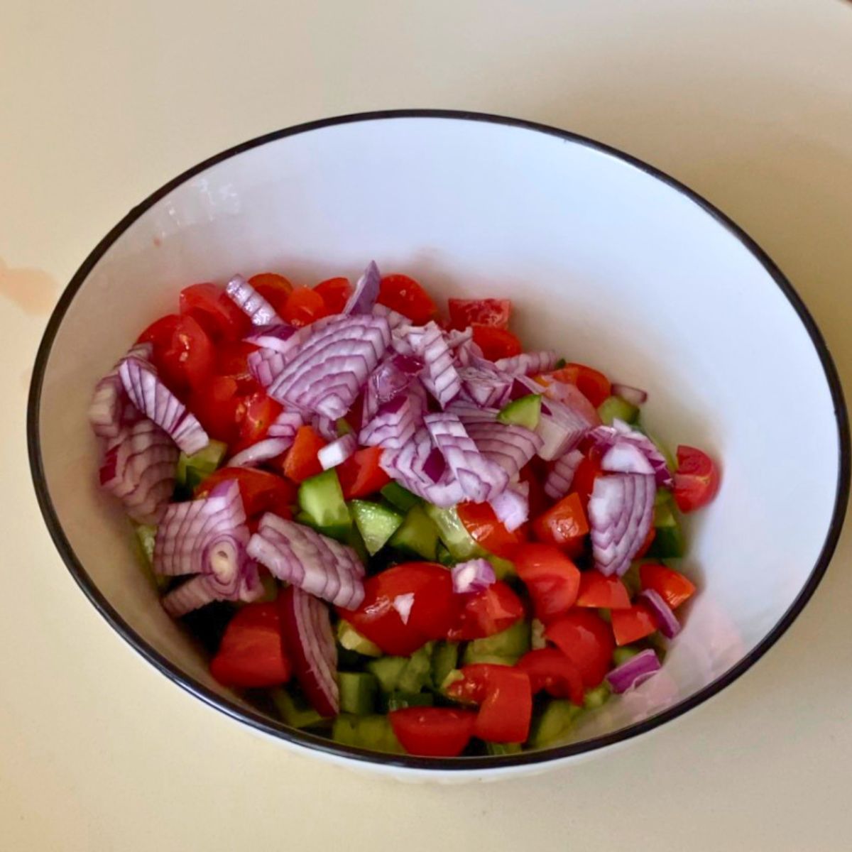 A white bowl with chopped veggies for salad.