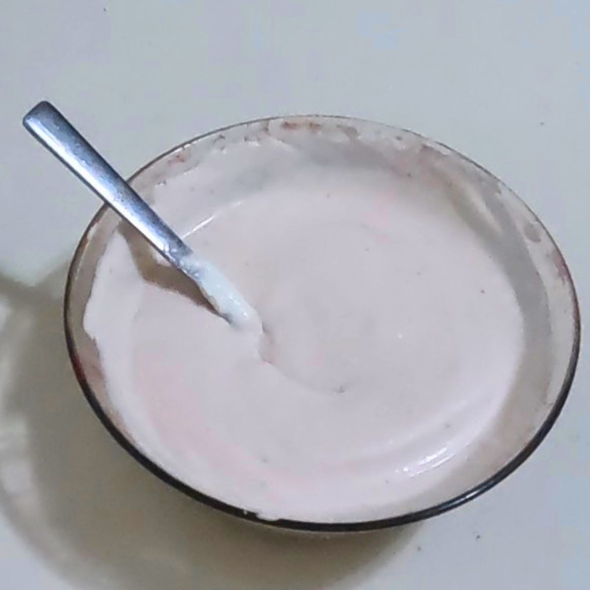 A glass bowl with strawberry mousse in light pink.