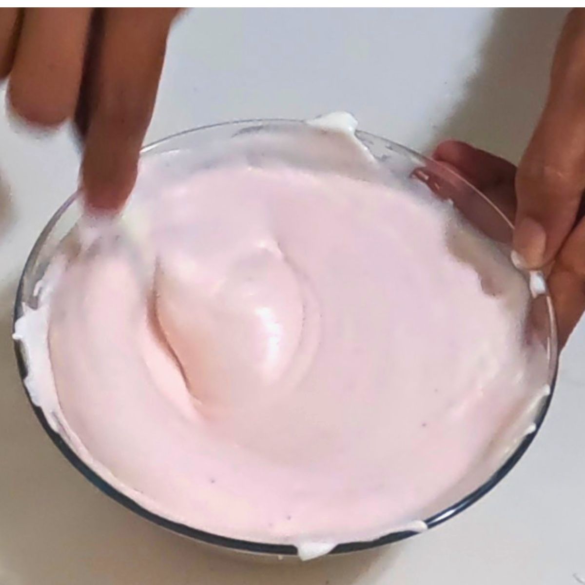 A glass bowl with pink strawberry mousse.