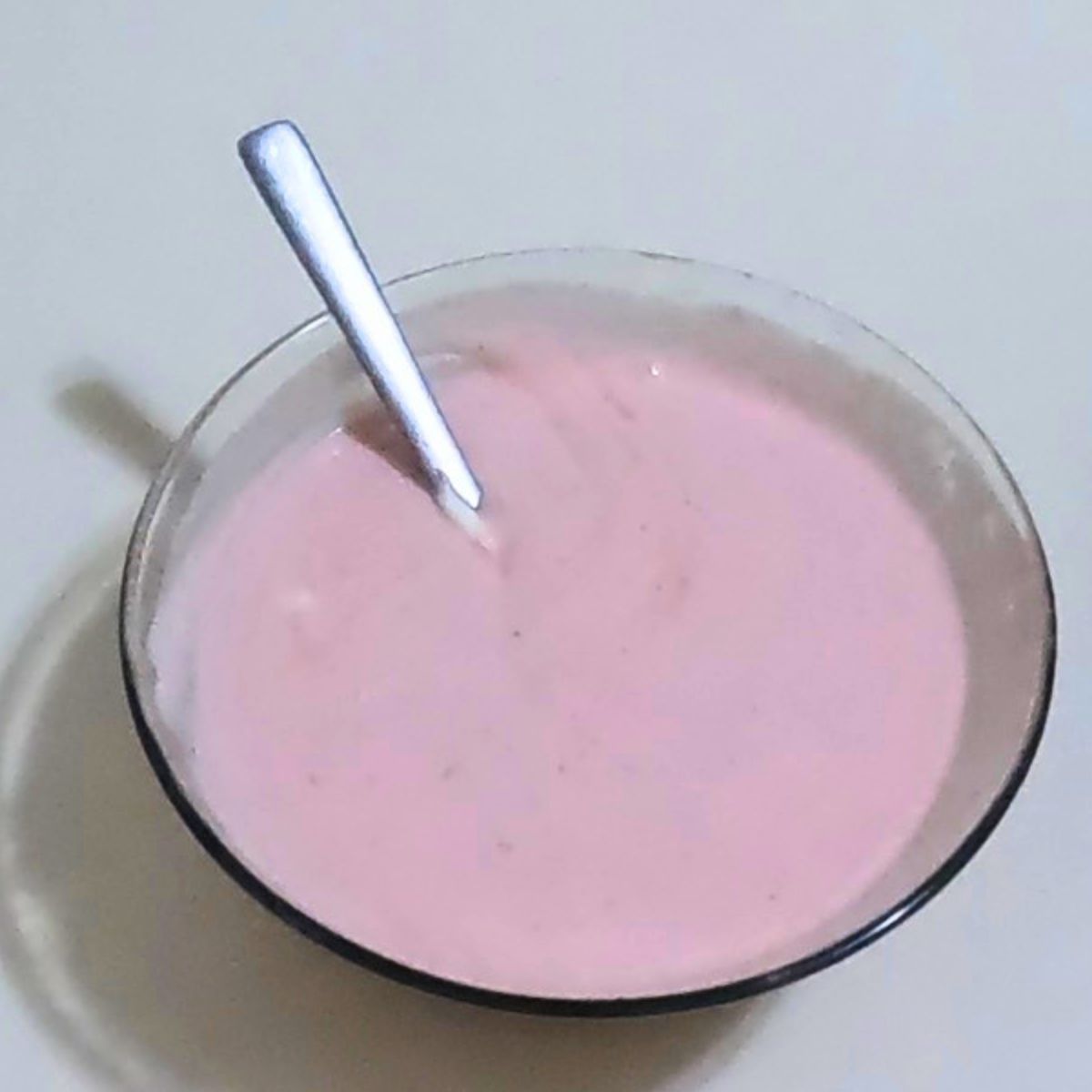 A glass bowl with pink strawberry mousse.